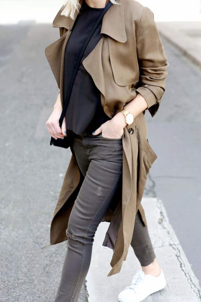 Jessie Bush wears traditional military khaki in this sophisticated outfit consisting of skinny jeans, a black tee, and a classic trench coat. We love the military aspect of this every day look. Trench: Dress Up, Tee/Jeans: Nobody, Bag: Saint Laurent.